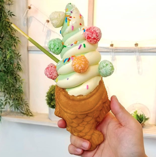 A beautiful fish cone with swirled yellow and green ice cream topped with gumdrops.