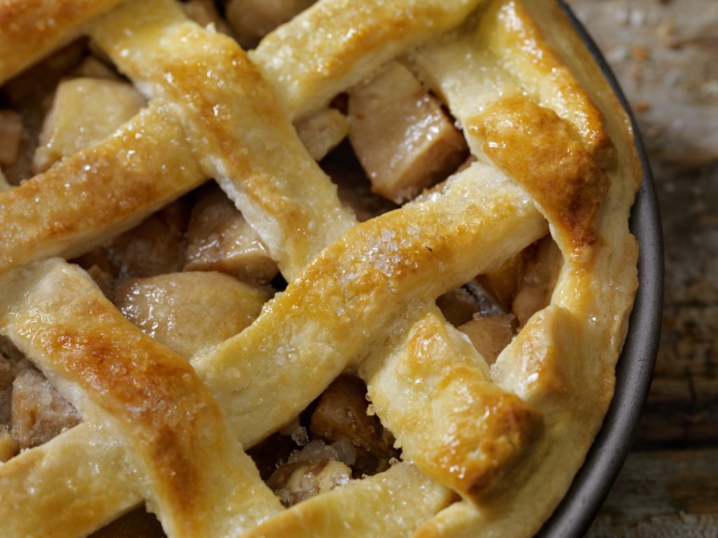 Une tarte aux pommes avec un fond de tarte en treillis et des morceaux de pommes qui dépassent.