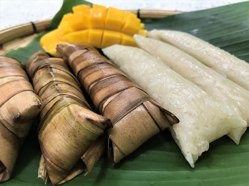 Suman wrapped in and served on banana leaves with mango. Suman enveloppé et servi sur des feuilles de banane à la mangue.