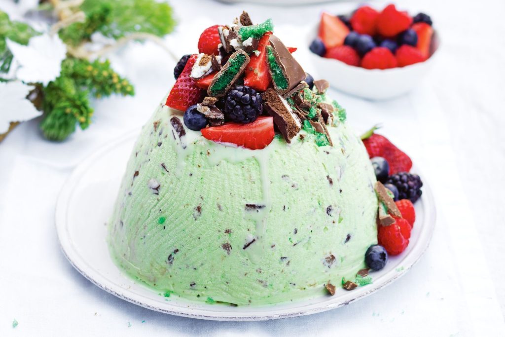A dome of mint ice cream with fresh fruits and shaved chocolate on top.