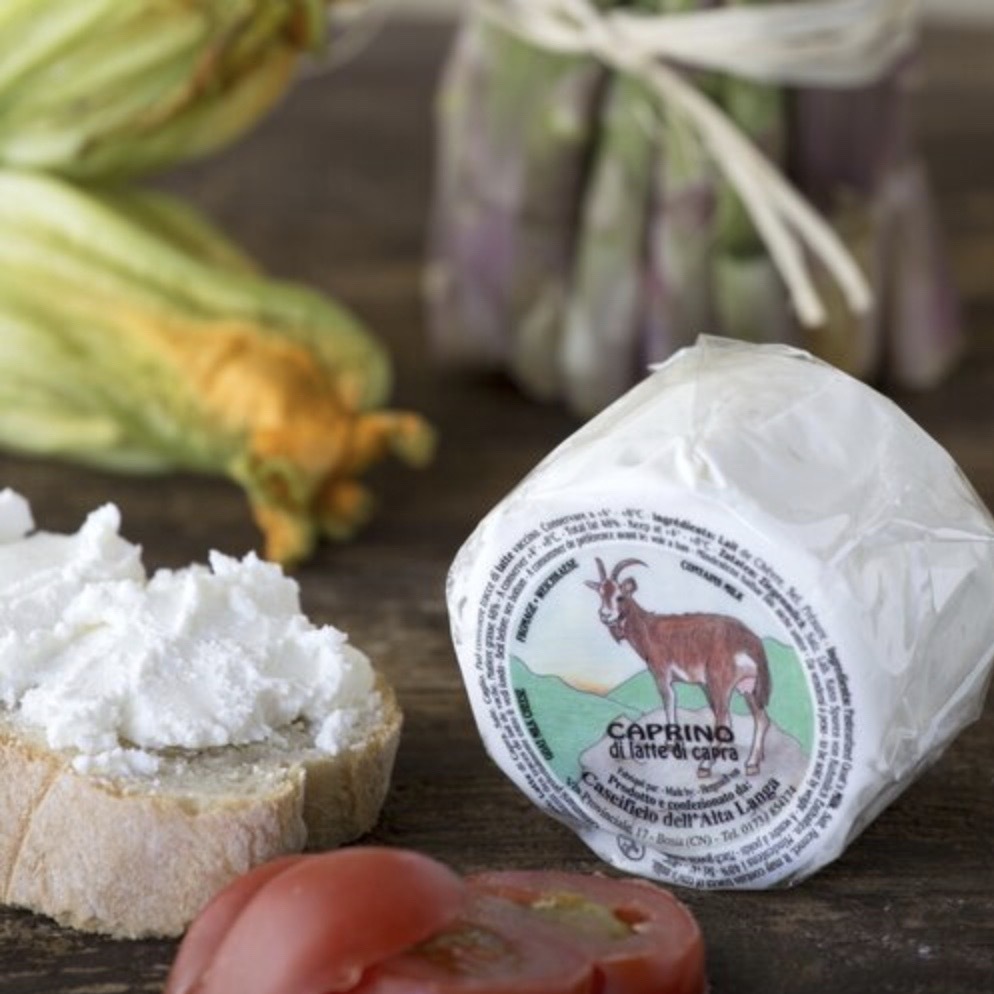 A small wheel of caprino beside the crumbly cheese on a slice of bread.