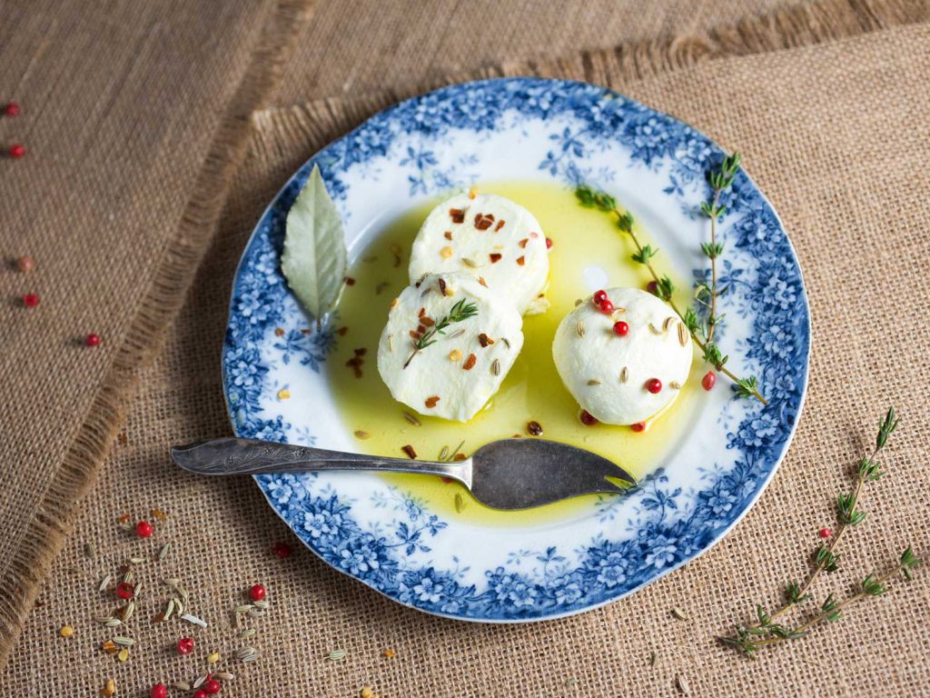 A blue and white plate with round slices of marinated goat cheese.