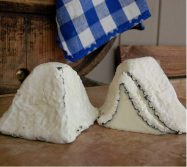 Two pyramids of cheese; one whole and one cut in half to reveal lines of mold.