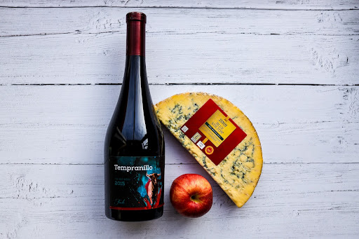 A bottle of wine, an apple and a blue Stilton