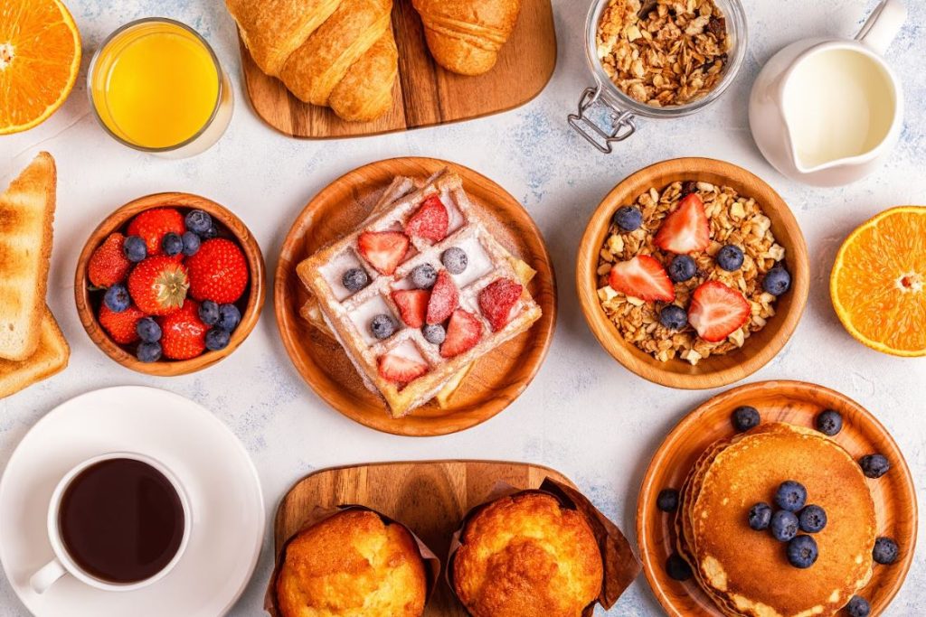 Breakfast table with waffles granola pastries and pancakes