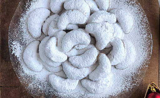 A plate of Kourabiedes shortbread cookies from Greece, topped with powdered sugar.