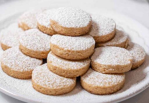 A plate of Spanish polvorones with powdered sugar.